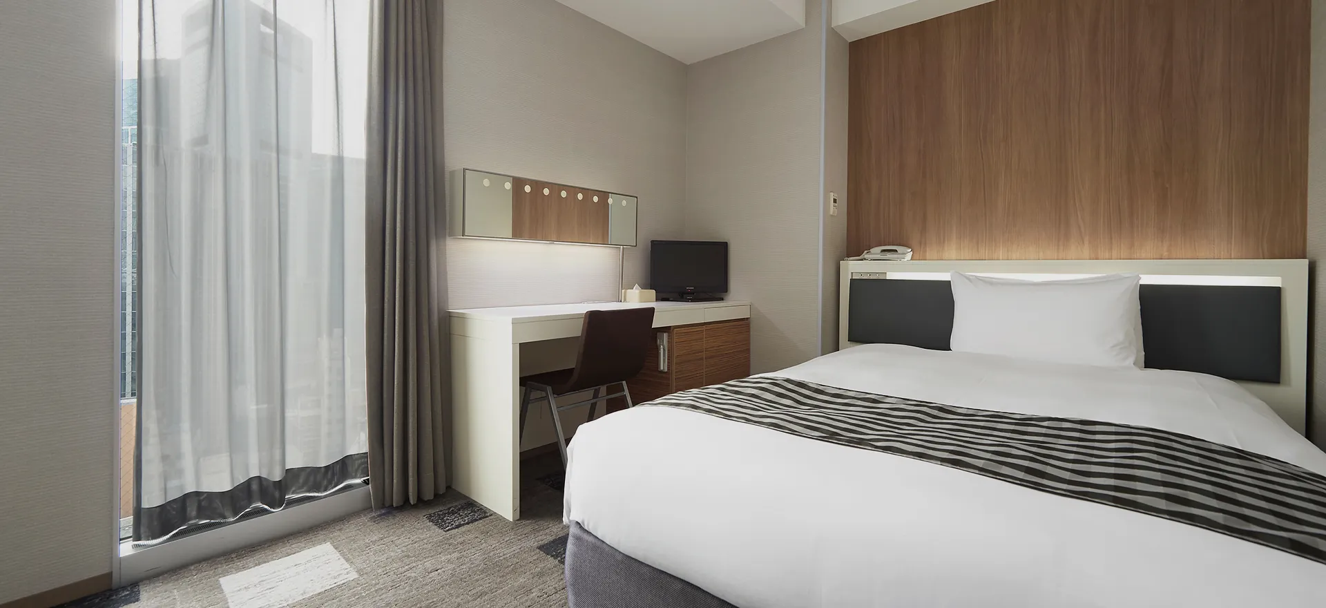 デスクとテレビを備えたシンプルで落ち着いたダブルルーム