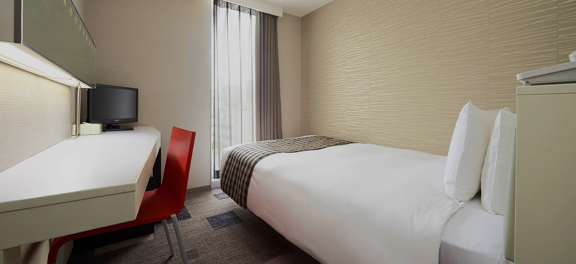 デスクと赤いチェアが配置された機能的なシングルルーム